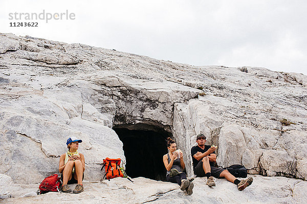 Drei Wanderer machen eine Wanderpause  sitzen neben einer Höhle  Mineral King  Sequoia National Park  Kalifornien  USA