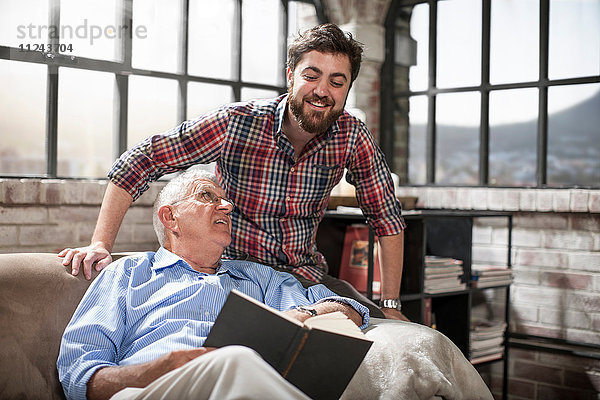 Vater und Sohn lesen Buch zu Hause