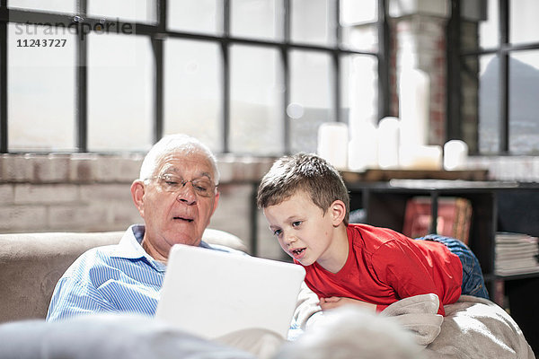 Großvater und Enkel mit digitalem Tablett zu Hause