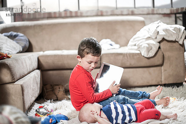 Junge zeigt digitales Tablett für kleine Schwester zu Hause