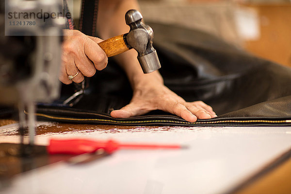 Mann hämmert Reißverschluss an Jacke bei Lederjackenherstellern  Nahaufnahme