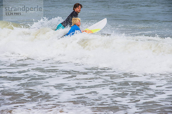 Vater und Sohn mit Surfbrettern im Meer und bereiten sich auf das Surfen vor