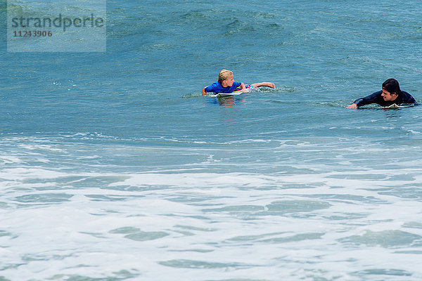 Vater und Sohn im Meer  paddeln auf Surfbrettern
