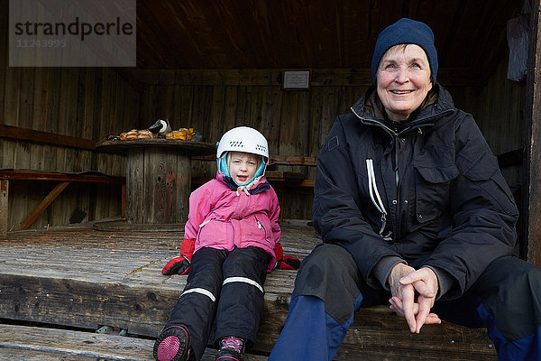 Mädchen mit Skihelm auf einer Scheunenstufe sitzend mit Grossmutter  Gavle  Schweden