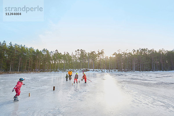 Älteres Ehepaar und Enkelkinder üben Eislaufslalom auf dem zugefrorenen See  Gavle  Schweden