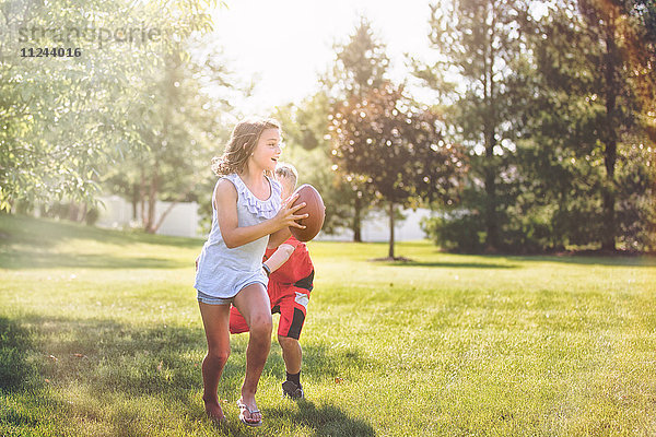 Mädchen und Junge spielen American Football