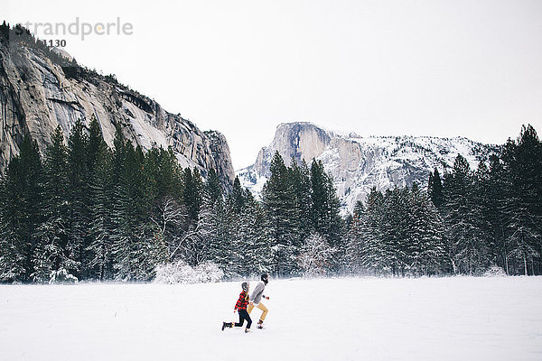 Seitenansicht eines Paares beim Laufen in schneebedeckter Landschaft