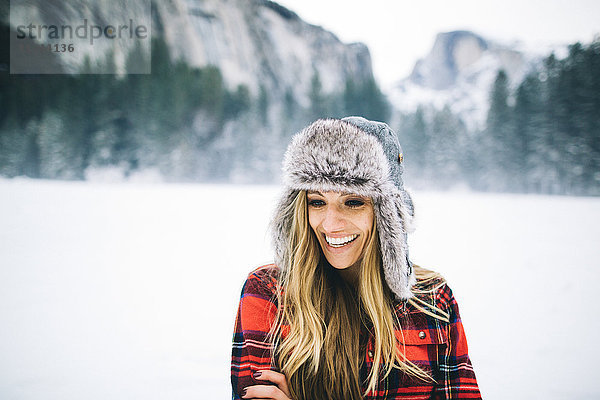 Rückansicht einer Frau mit Uschanka-Hut auf schneebedeckter Landschaft