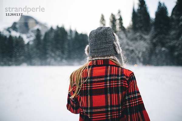 Frau mit Ushanka-Hut auf schneebedeckter Landschaft