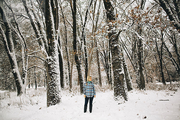 Frau steht in schneebedecktem Wald und schaut weg