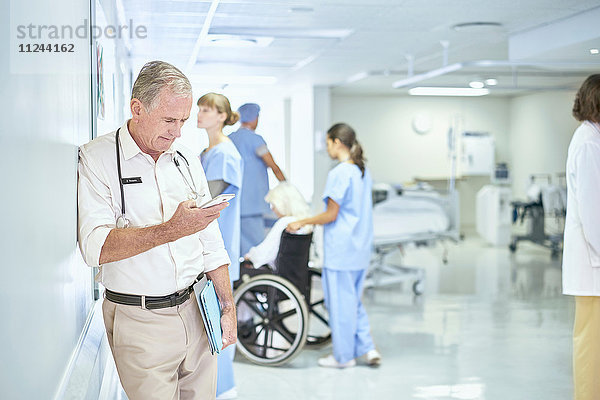 Leitender Arzt liest Smartphone-Nachricht auf der Krankenhausstation