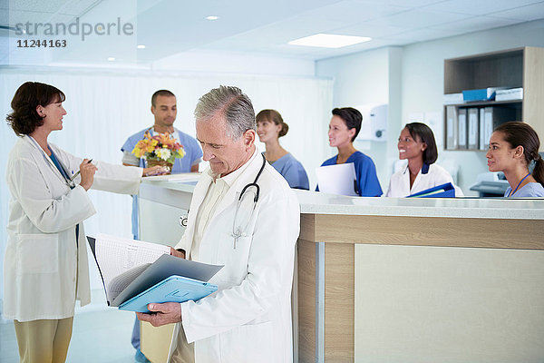 Leitender Arzt liest medizinische Notizen auf der Krankenschwesternstation