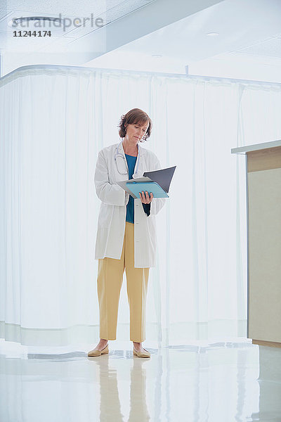 Ärztin liest medizinische Notizen auf der Schwesternstation im Krankenhaus