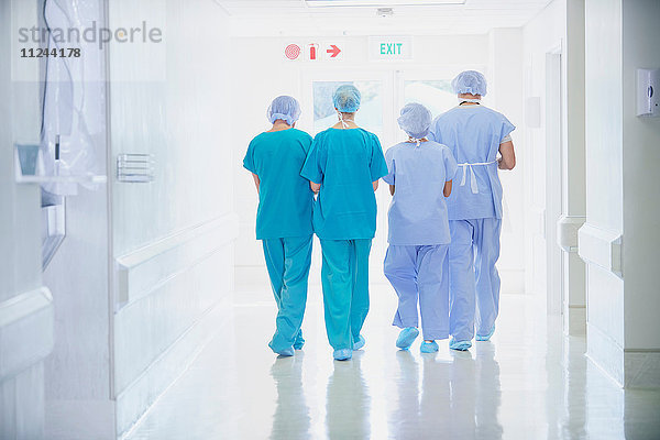 Rückansicht von vier medizinischen Mitarbeitern in Kitteln  die im Krankenhauskorridor gehen