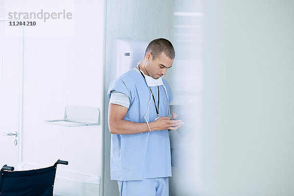 Männlicher Arzt benutzt Smartphone auf der Krankenhausstation