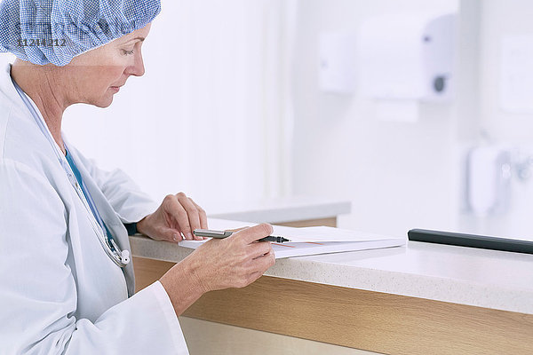 Ärztin schreibt medizinische Notizen auf der Schwesternstation im Krankenhaus
