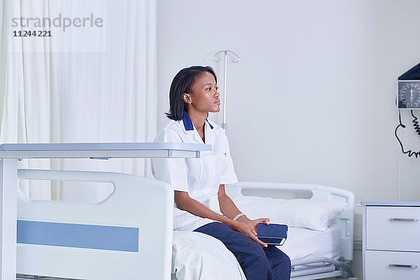 Ärztin sitzt und starrt vom Krankenhausbett aus