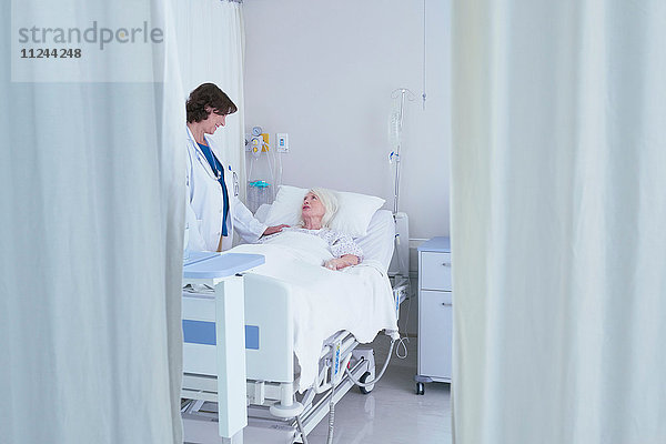 Ärztin im Gespräch mit älterer Patientin im Krankenhausbett