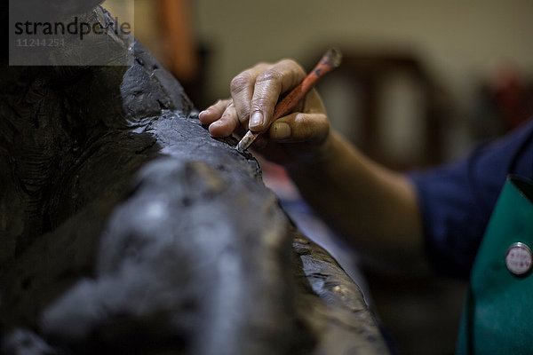 Ausschnitt eines Bildhauers im Atelier eines Künstlers  der mit einem Handwerkzeug Skulpturen schafft