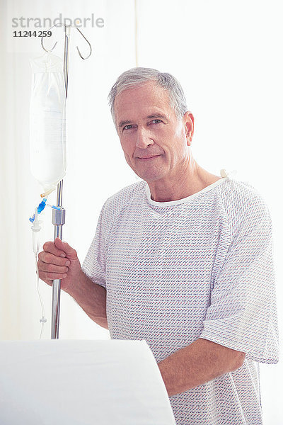 Porträt eines älteren männlichen Patienten mit intravenösem Tropf im Krankenhaus