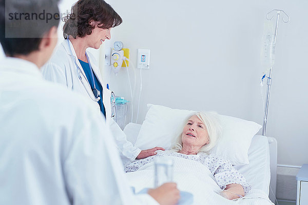 Ärzte erklären einer älteren Patientin im Krankenhausbett