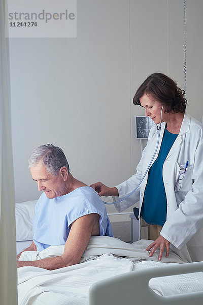 Ärztin hört älteren männlichen Patienten mit dem Stethoskop zu