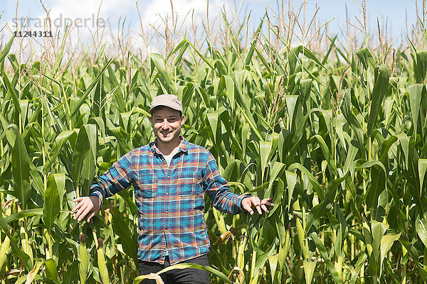 Landwirt im Maisfeld schaut lächelnd in die Kamera