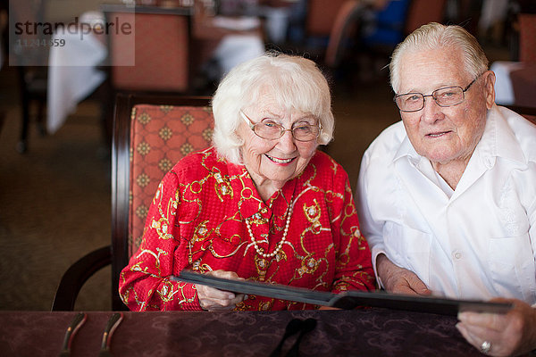 Porträt eines älteren Ehepaares  das lächelnd am Tisch im Restaurant sitzt