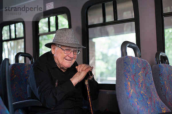 Porträt eines älteren Mannes  der im Zug sitzt und einen Spazierstock hält