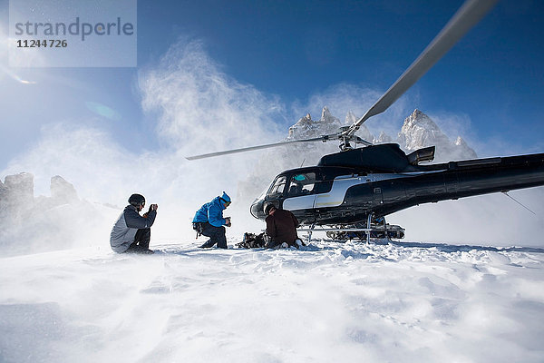 Drei männliche Snowboarder steigen aus Hubschrauber aus  Trient  Schweizer Alpen  Schweiz