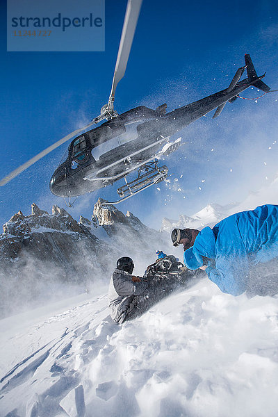 Hubschrauber verlässt männliche Snowboarder am Berg  Trient  Schweizer Alpen  Schweiz