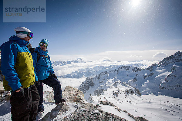 Zwei männliche Snowboarder mit Blick auf die schneebedeckte Landschaft  Trient  Schweizer Alpen  Schweiz