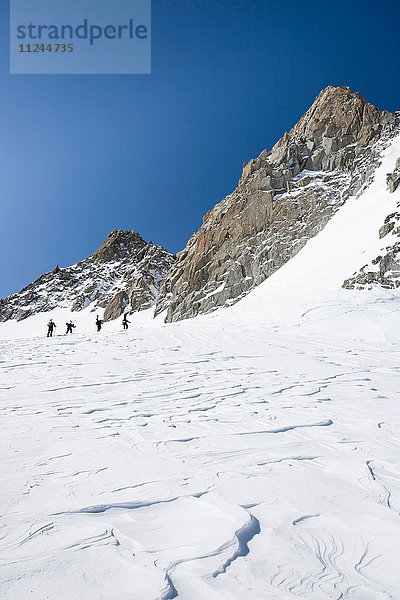 Vier männliche Snowboarder wandern durch eine verschneite Landschaft  Trient  Schweizer Alpen  Schweiz