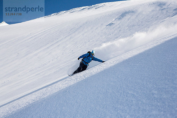 Männlicher Snowboarder beim Snowboarden den steilen Berg hinunter  Trient  Schweizer Alpen  Schweiz