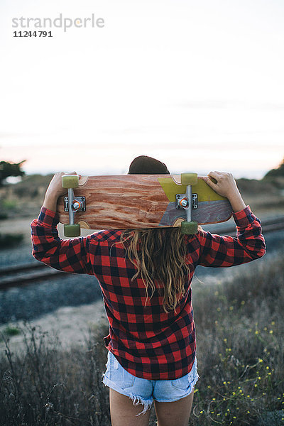 Frau mit Skateboard auf den Schultern