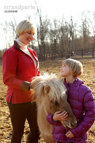 Mutter und Tochter im Freien  stehend mit Pony