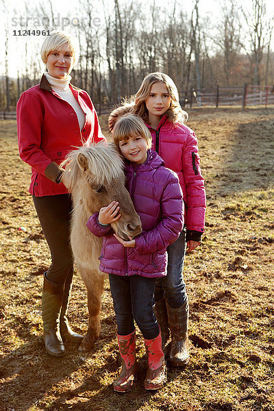 Porträt von Mutter und Töchtern  stehend mit Pony