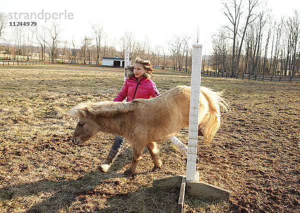 Junges Mädchen im Freien  das Pony über die Stange führt