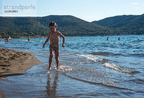 Junge paddelt in den Wellen an der Küste  Italien