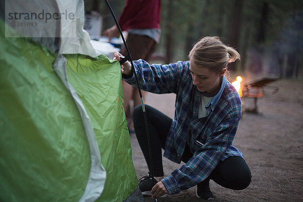 Junge Frau kauert  um in der Abenddämmerung ein Zelt vorzubereiten  Mammoth Lakes  Kalifornien  USA