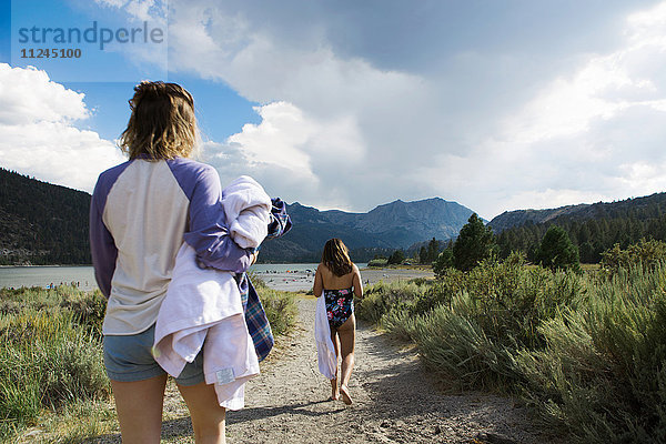 Rückansicht von zwei jungen Frauen  die mit Handtüchern zum See schlendern  Mammoth Lakes  Kalifornien  USA