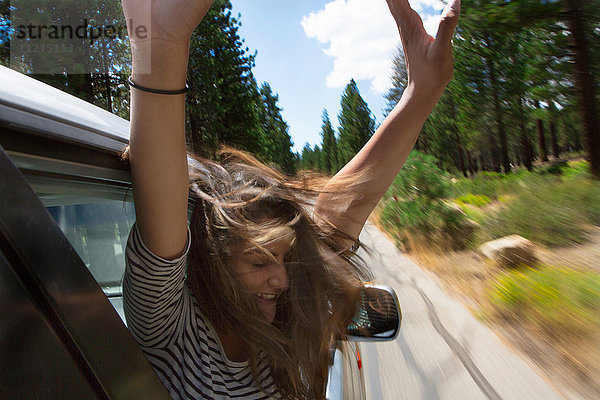 Junge Frau  die sich aus einem fahrenden Autofenster lehnt  Mammoth Lakes  Kalifornien  USA