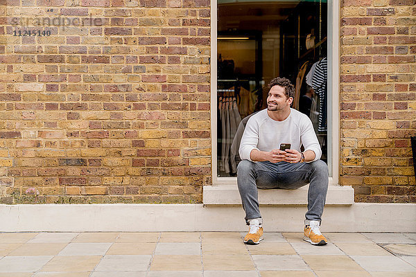 Junger Mann mit Smartphone vor der Tür  Kings Road  London  UK