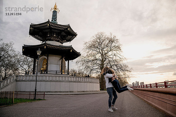 Romantischer junger Mann hebt seine Freundin im Battersea Park  London  Großbritannien