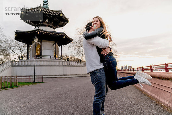 Glücklicher junger Mann umarmt Freundin im Battersea Park  London  Großbritannien