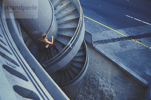 Junge Frau läuft im Freien eine Wendeltreppe hinauf
