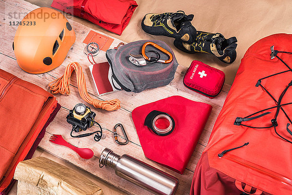 Draufsicht auf das Packen der Kletterausrüstung mit Erste-Hilfe-Kasten  Kletterhelm  Rucksack und Kletterseilen