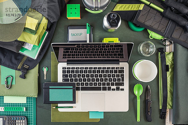Draufsicht auf Laptop  externe Festplatte und Wanderausrüstung  grün