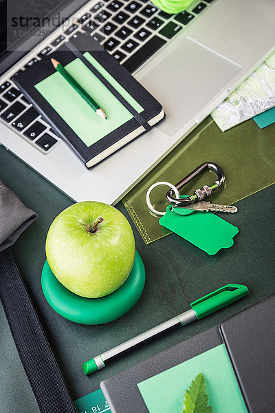Laptop  Notizbuch  Faltkarte und grüner Apfel auf dem Tisch