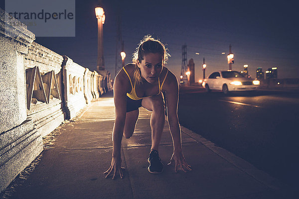 Junge Frau in Startposition vor dem Lauf